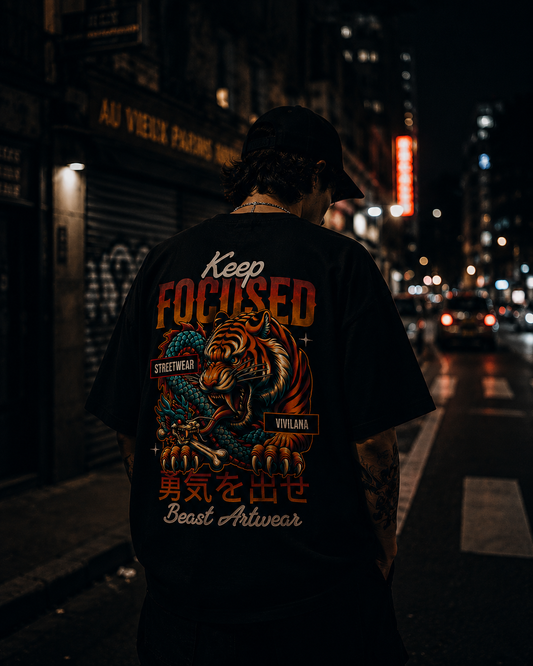 Man wearing black 'Keep Focused' tiger graphic tee on city street at night, streetwear style.
